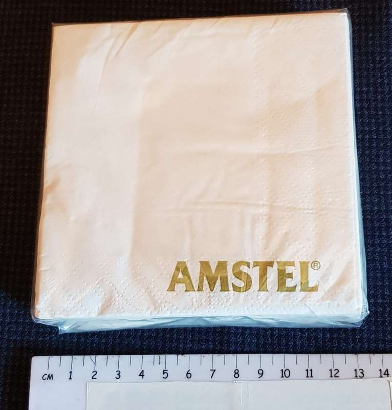 Serviettes: Sealed packet of white drinks serviettes branded Amstel in gold lettering.
