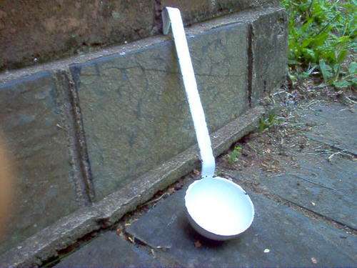 ENAMEL SOUP LADLE IN WHITE WITH BLACK TRIM.