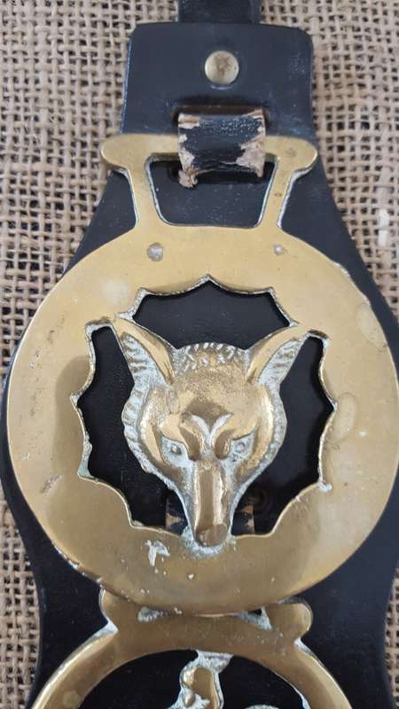 A TRIO OF OLD HORSE BRASSES ON A LEATHER STRAP
