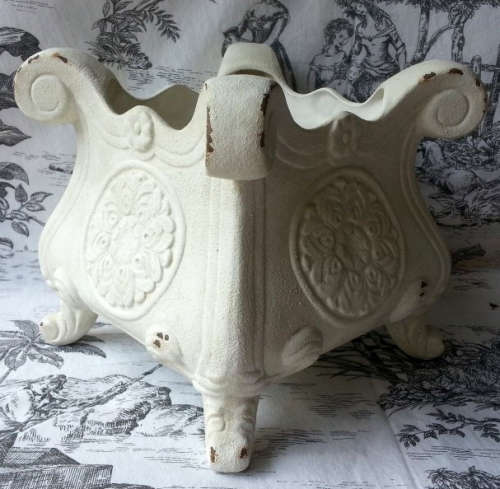 ATTRACTIVE, PAINTED OFF WHITE, ANTIQUED METAL POT PLANT HOLDER ON FOUR LEGS.