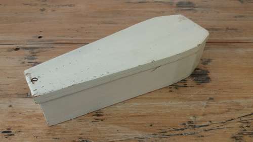 A wooden carving of a man in a box, shaped like a coffin, 25cm 9cm x 6cm