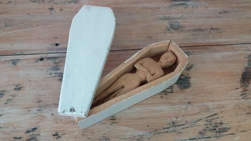 A wooden carving of a man in a box, shaped like a coffin, 25cm 9cm x 6cm