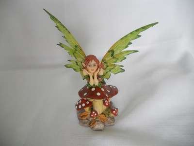 Fairy with big green wings leaning on toadstool