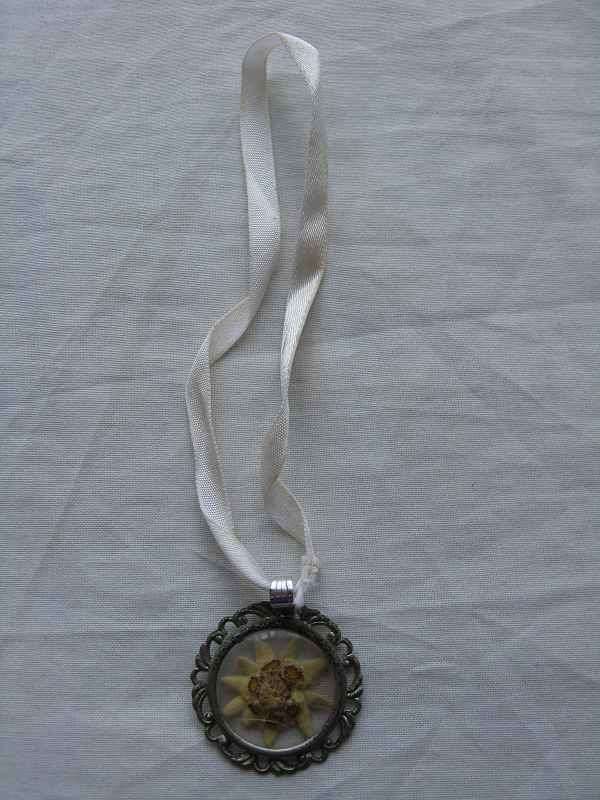 RIBBON NECKLACE WITH POSSIBLY FLOWER IN INNER OF PENDANT. D 3.2cm