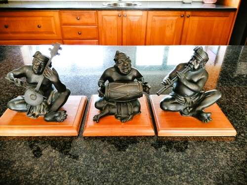 Set of three Balinese patinated bronze figures of seated musician, on wooden bases