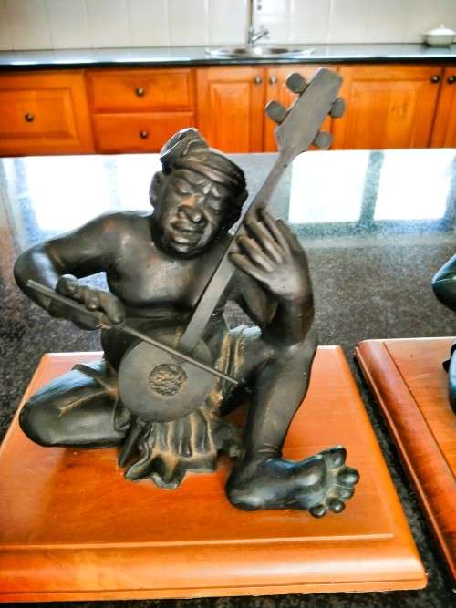 Set of three Balinese patinated bronze figures of seated musician, on wooden bases
