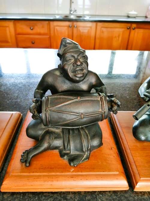Set of three Balinese patinated bronze figures of seated musician, on wooden bases