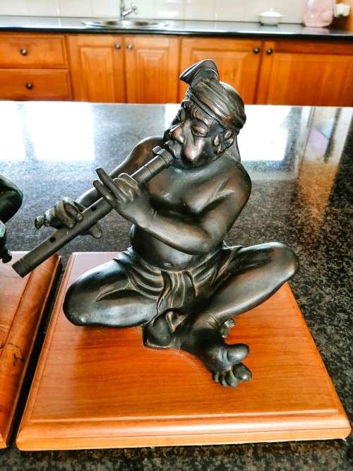 Set of three Balinese patinated bronze figures of seated musician, on wooden bases