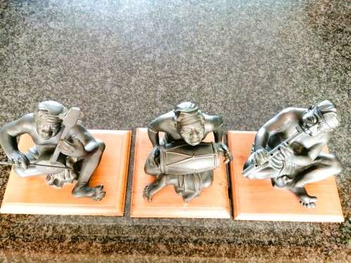 Set of three Balinese patinated bronze figures of seated musician, on wooden bases