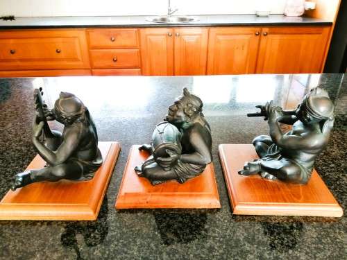 Set of three Balinese patinated bronze figures of seated musician, on wooden bases