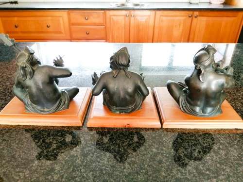 Set of three Balinese patinated bronze figures of seated musician, on wooden bases