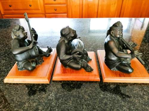 Set of three Balinese patinated bronze figures of seated musician, on wooden bases