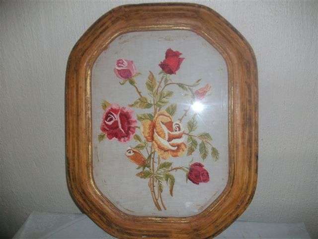 Vintage wooden oval framed rose tapestry behind glass