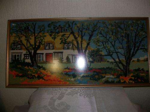 Framed country cottage scene tapestry behind glass