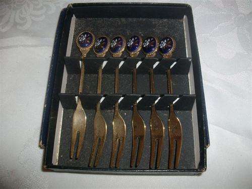 A set of gold plated pickle forks with a blue porcelain flower top