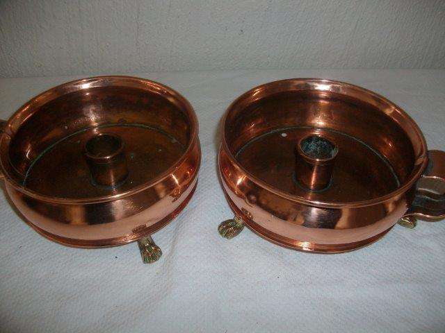 A pair of copper with brass feet candle holders