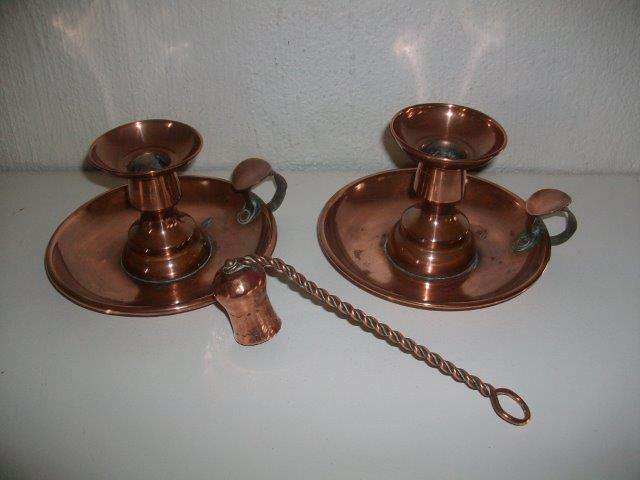 A pair of copper candle holders with candle snuffer