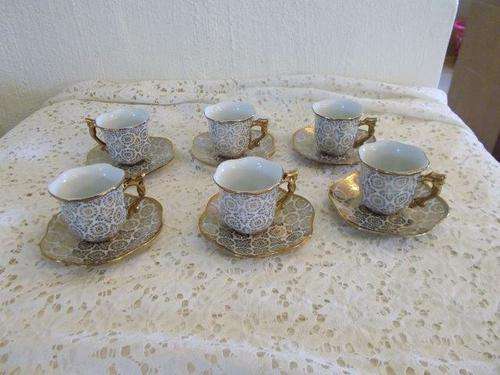 A set of six small gold coffee cups and saucers