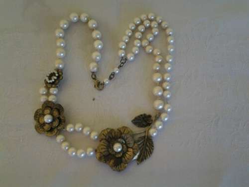 very pretty pearl like beaded necklace with a fancy metal flower in between