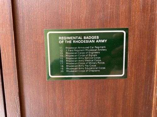 RHODESIAN BADGES OF THE REGIMENTS AND CORPS OF THE FORMER ARMY,PRESENTED IN A CUSTOM MADE CABINET OF