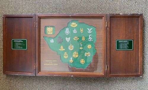 RHODESIAN BADGES OF THE REGIMENTS AND CORPS OF THE FORMER ARMY,PRESENTED IN A CUSTOM MADE CABINET OF