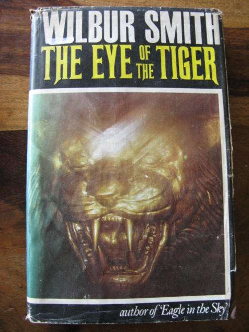 WILBUR SMITH - THE EYE OF THE TIGER - 1ST EDITION PUBLISHED 1975 HARDCOVER WITH DUSTCOVER