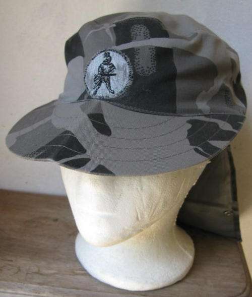 AWB YSTERGARDE CAMO FLAP CAP COMPLETE WITH BADGE-INSIDE RING MEASURES 53CM-GOOD CONDITION WITHOUT AN