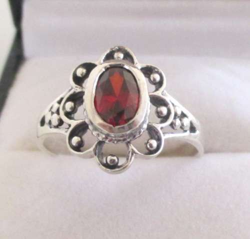 A SOLID SILVER RING WITH A RED CZ STONE