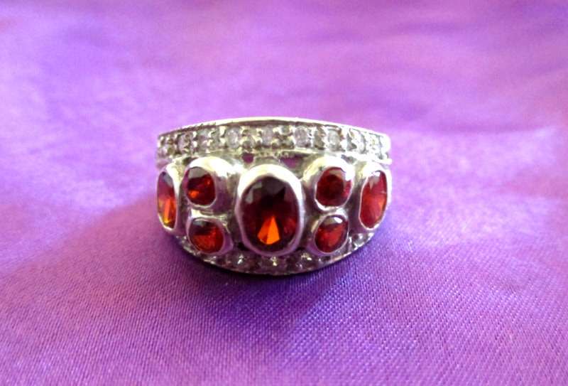 A SOLID SILVER RING WITH RED STONES