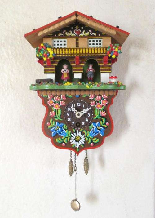 A DECORATIVE WALL CLOCK WITH IT'S KEY--TICKING AWAY
