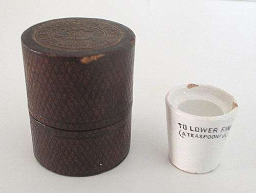 AN ANTIQUE  MINIATURE MEDICINE MEASURE IN IT'S ORIGINAL LEATHER CONTAINER
