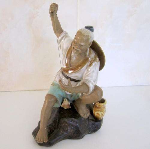 A POTTERY FIGURE OF A JAPANESE MAN CATCHING FISH