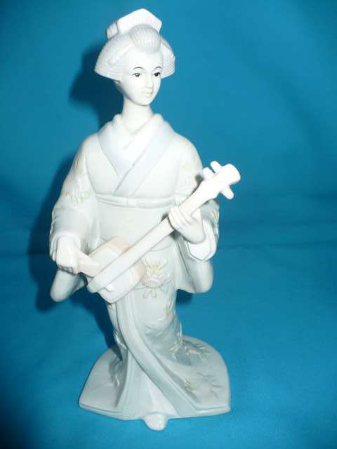 CERAMIC FIGURINE OF A GEISHA PLAYING AN INSTRUMENT