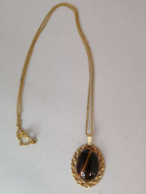 A PRETTY TIGERS EYE PENDANT ON A GOLD CHAIN MARKED NS