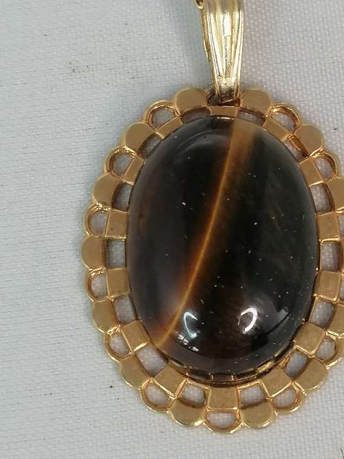 A PRETTY TIGERS EYE PENDANT ON A GOLD CHAIN MARKED NS
