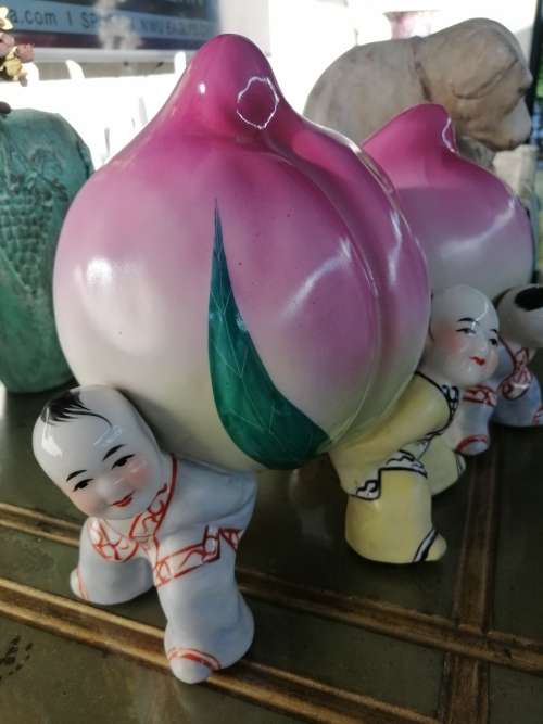 TWO CHINESE PORCELIAN STATUETTES CHILDREN CARRYING A RIPE PEACH