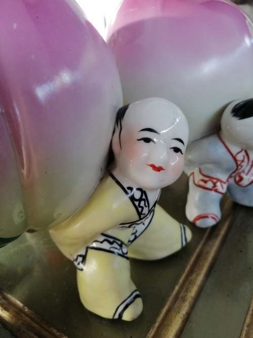 TWO CHINESE PORCELIAN STATUETTES CHILDREN CARRYING A RIPE PEACH