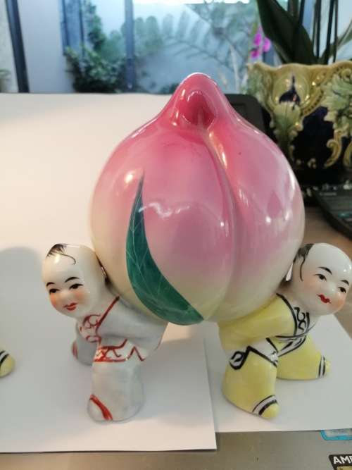 TWO CHINESE PORCELIAN STATUETTES CHILDREN CARRYING A RIPE PEACH
