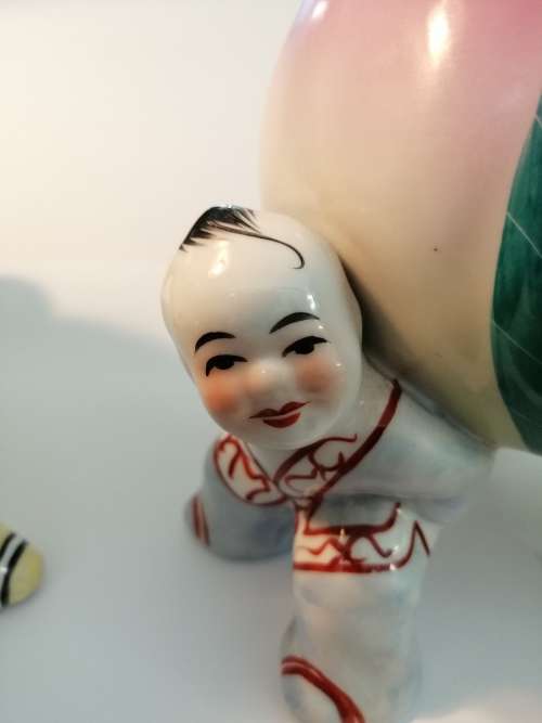TWO CHINESE PORCELIAN STATUETTES CHILDREN CARRYING A RIPE PEACH
