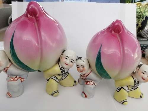 TWO CHINESE PORCELIAN STATUETTES CHILDREN CARRYING A RIPE PEACH
