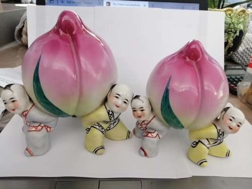 TWO CHINESE PORCELIAN STATUETTES CHILDREN CARRYING A RIPE PEACH
