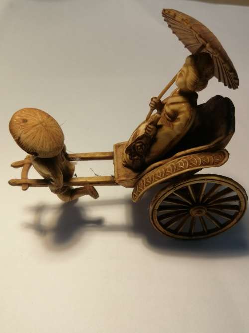 A VINTAGE JAPANESE CELLULIOD FIGURINE OF A GEISHA GIRL ON A RICKSHAW