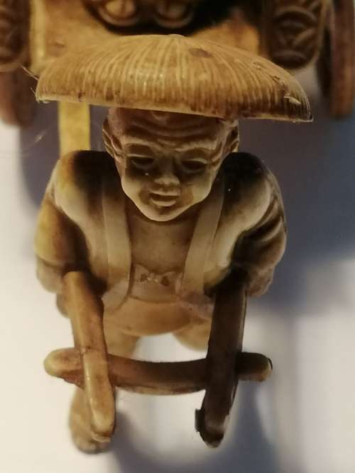 A VINTAGE JAPANESE CELLULIOD FIGURINE OF A GEISHA GIRL ON A RICKSHAW