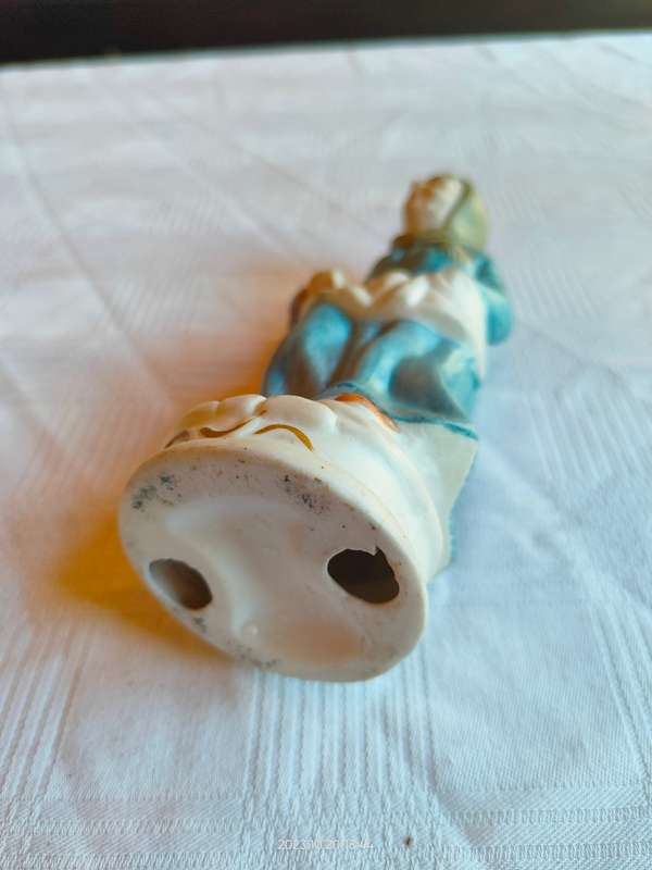A vintage figurine of an old lady carrying grapes in a basket