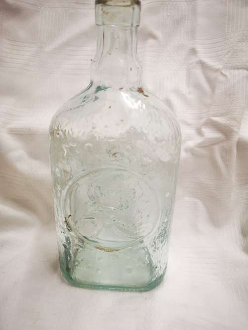 Vintage glass bottle with sun on one side and moon on the other