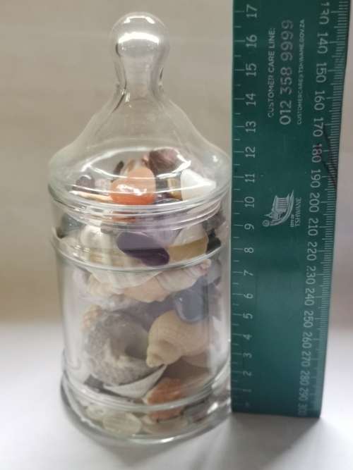 Big lot of sea shells and some semi-precious stones in a glass bottle.