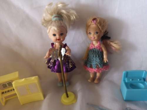 Two small Barbie's sister-like dolls with toy furniture.