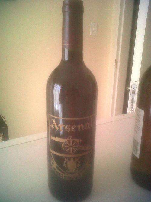 Red bottle of wine with ARSENAL Soccer teams' logo engraved on bottle