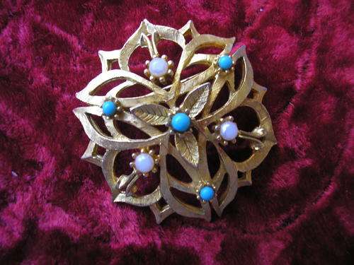 GOLD COLOURED BROOCH WITH WHITE AND BLUE BEADS.