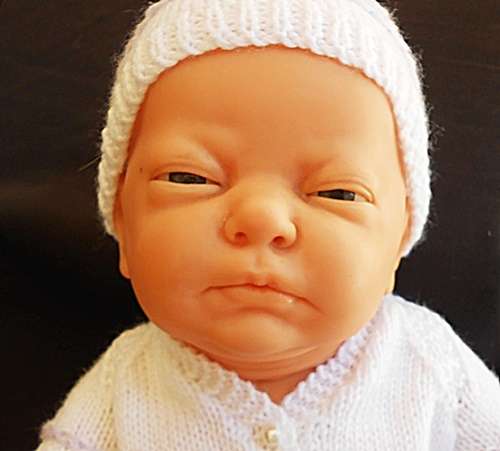 Newborn baby girl doll in new outfit knitted for her.